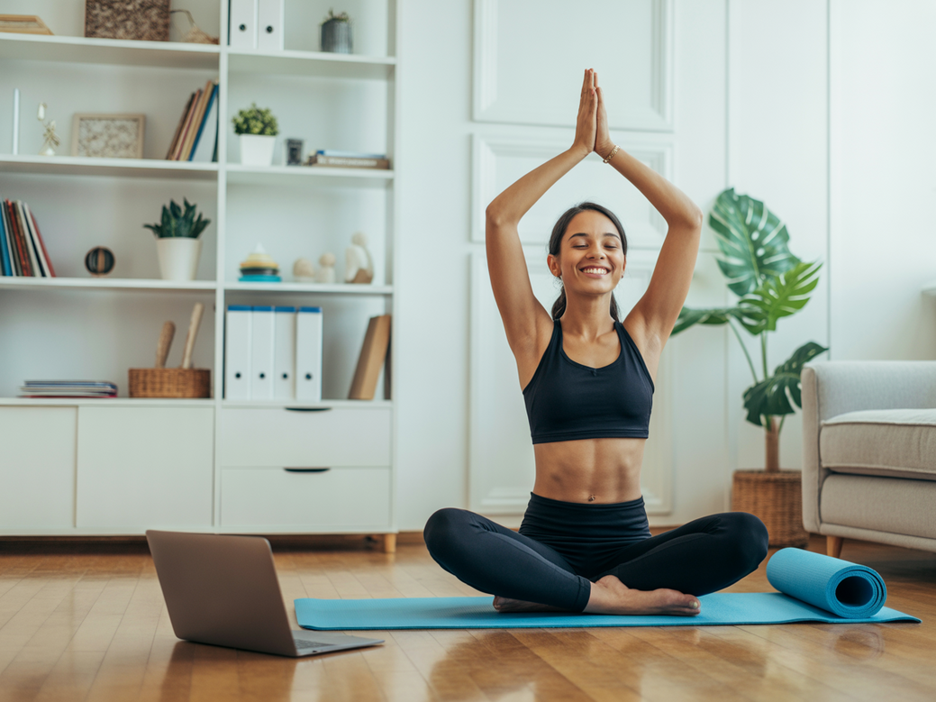 Empreendedora digital praticando yoga ao lado de seu laptop, demonstrando o equilíbrio e o bem-estar para empreendedoras.