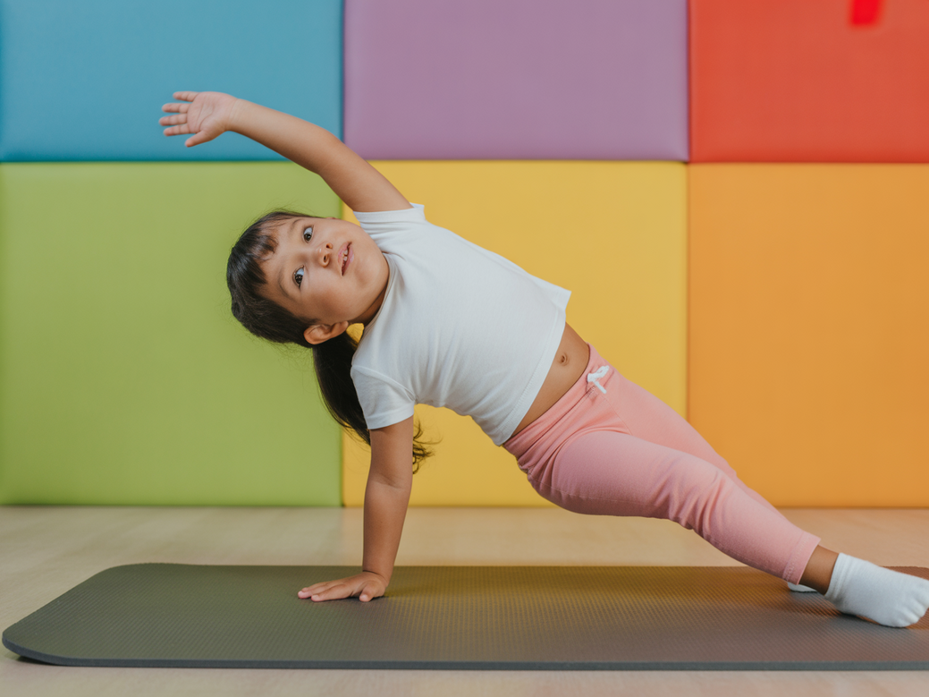 Criança com autismo praticando Pilates adaptado com a ajuda de uma educadora, usando frases de Pilates para se inspirar.