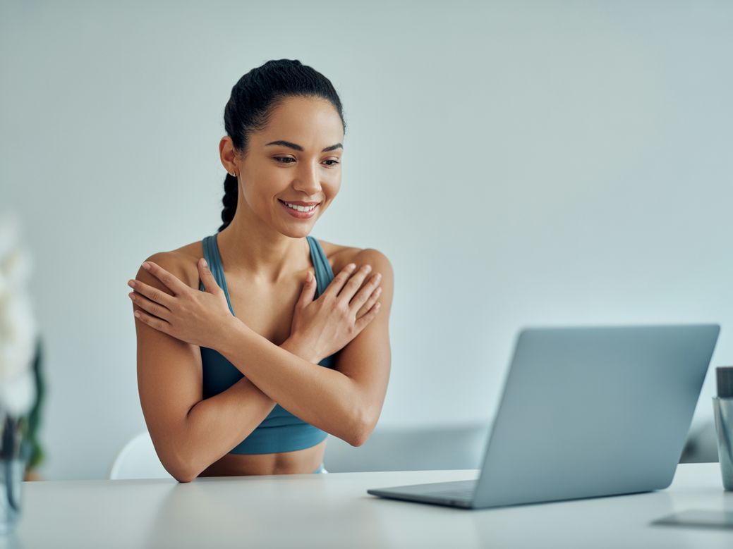 Instrutora de alongamento dando aula online em um estúdio em casa, demonstrando profissionalismo e tecnologia para ensinar a elevação pélvica.
