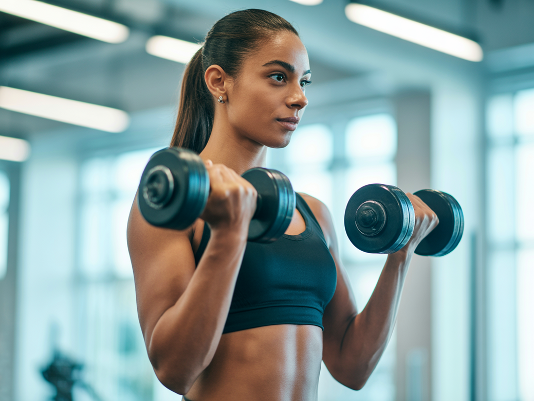 Personal trainer vegano demonstrando um treino com halteres para veganos focado em hipertrofia.